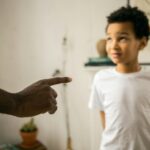 Upset little ethic boy looking at faceless father during argument