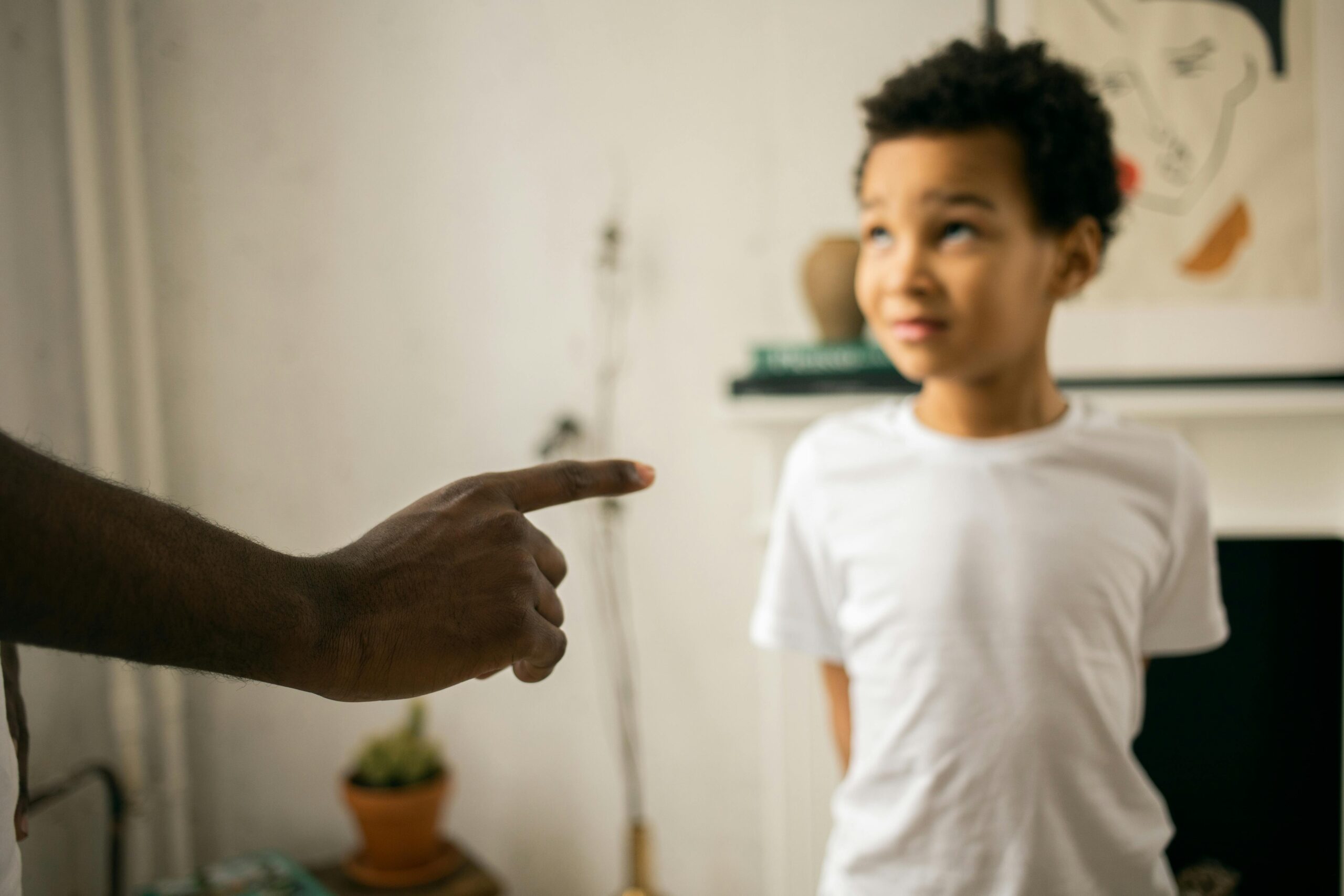 Upset little ethic boy looking at faceless father during argument