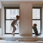 Two children playing on a window seat in a cozy indoor setting, showcasing joy and family bonds.