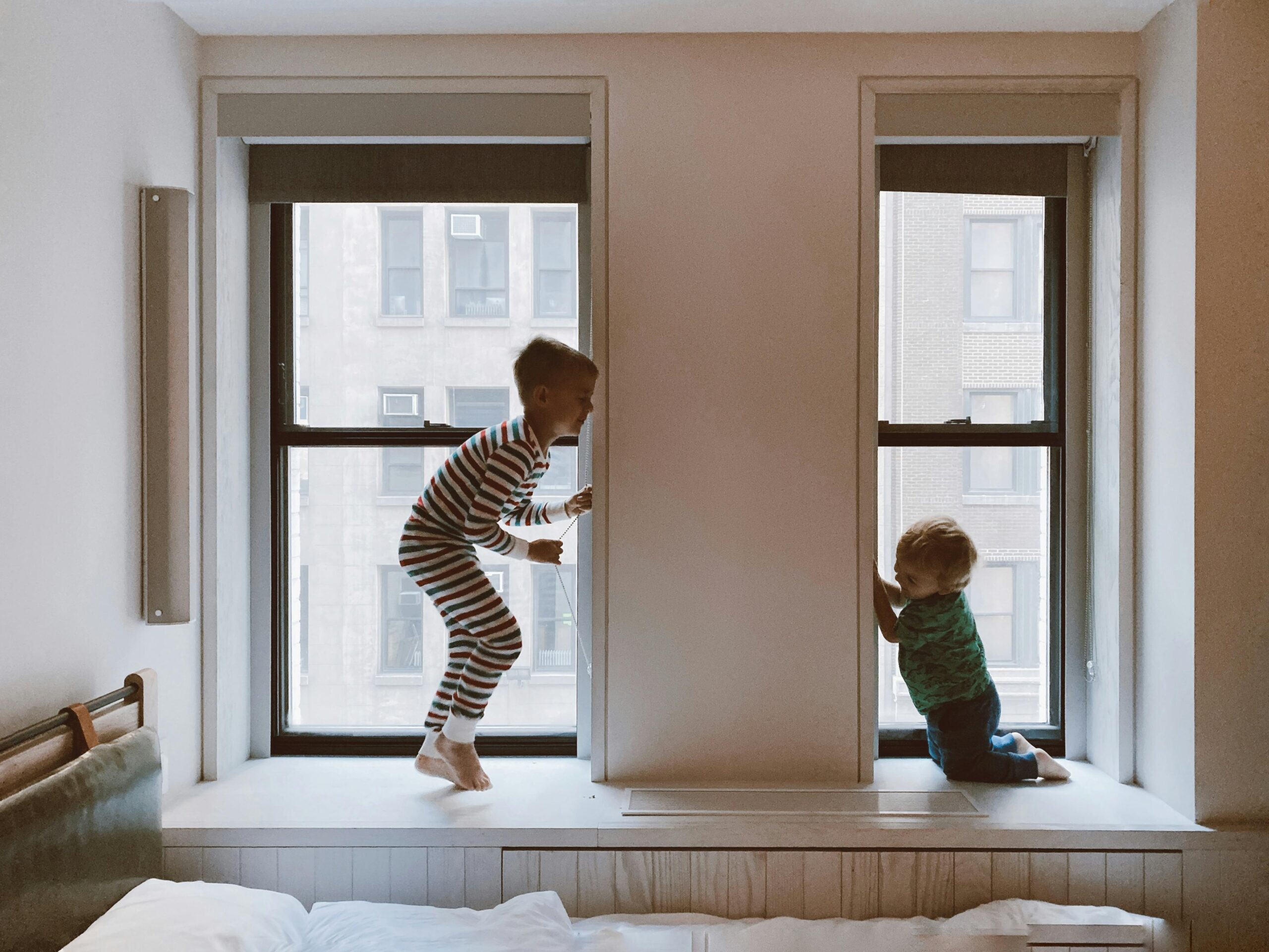 Two children playing on a window seat in a cozy indoor setting, showcasing joy and family bonds.