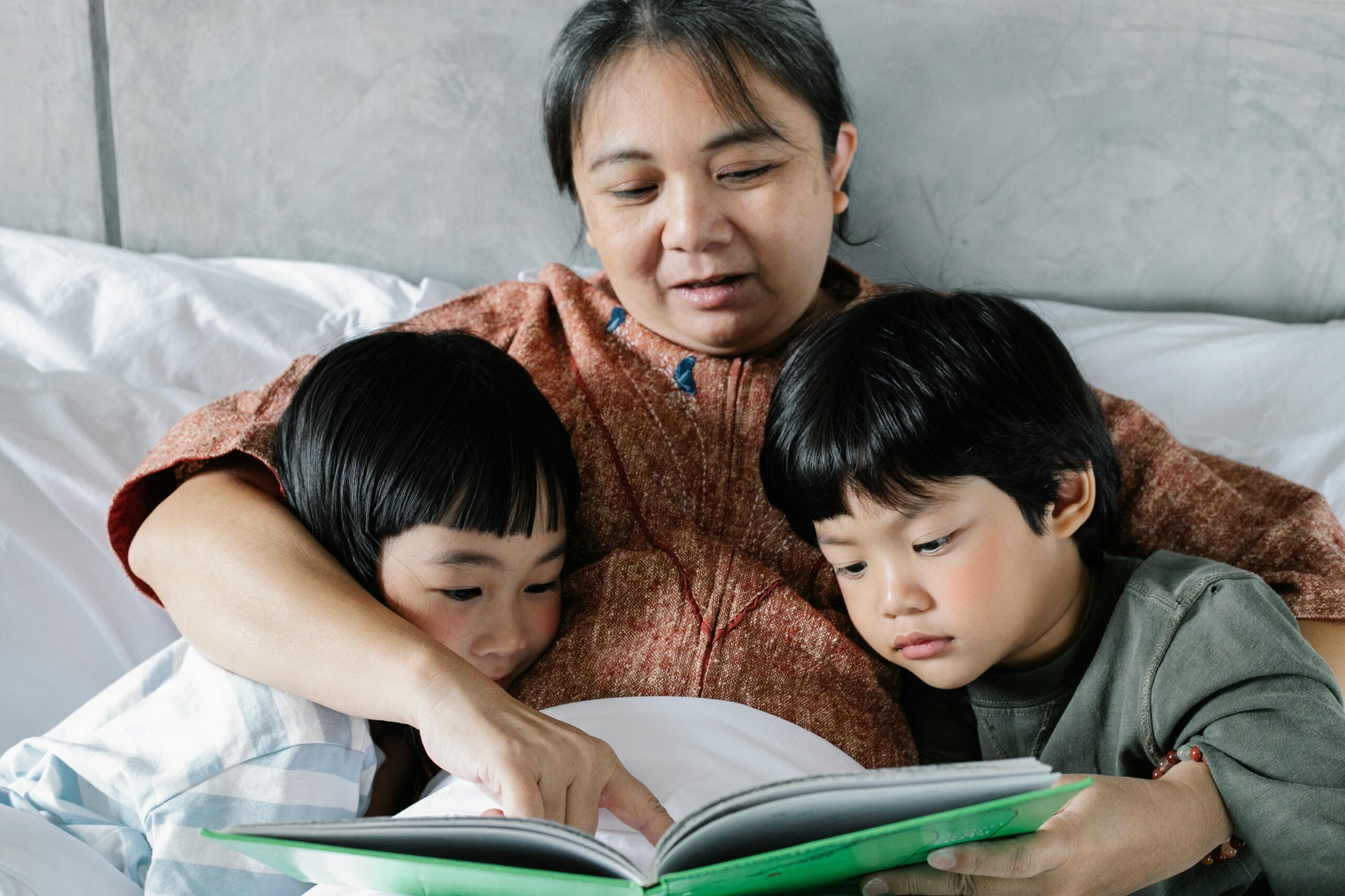 A mother reads a storybook to her two children, creating a cozy and warm bedtime moment.